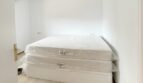 Schlafzimmer mit neuem Doppelbett in originalverpackten Matratzen, heller Holzboden, weiße Wände, Zweifamilienhaus Portocolom
