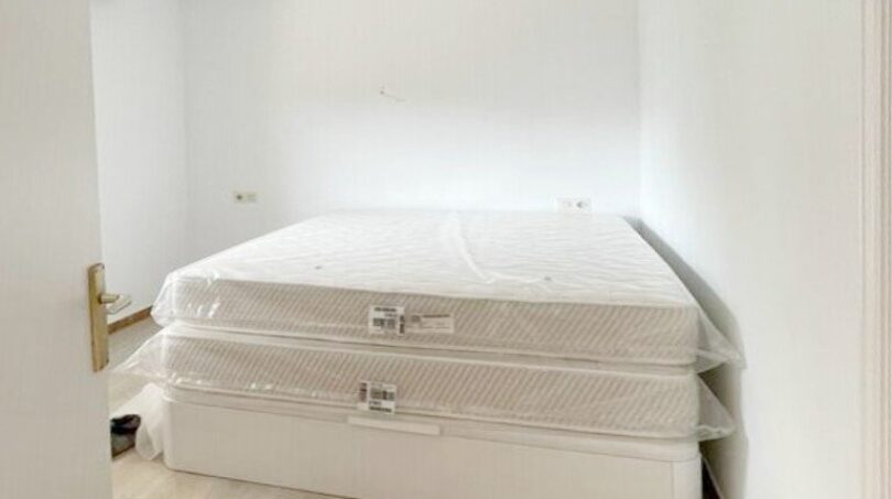 Schlafzimmer mit neuem Doppelbett in originalverpackten Matratzen, heller Holzboden, weiße Wände, Zweifamilienhaus Portocolom