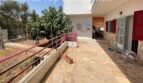 Terrasse mit Natursteinboden, rotem Geländer und Gartenblick des Zweifamilienhauses in Portocolom