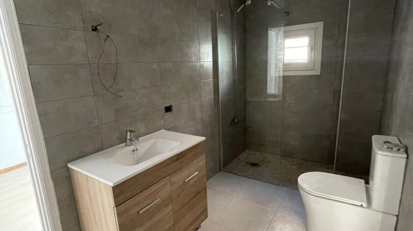 Modernes Badezimmer mit walk-in Dusche, Holzunterschrank und WC im Zweifamilienhaus Portocolom