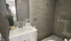 Modernes Badezimmer mit grauer Fliesenoptik, weißem Waschtisch, Dusche und WC im Zweifamilienhaus Portocolom