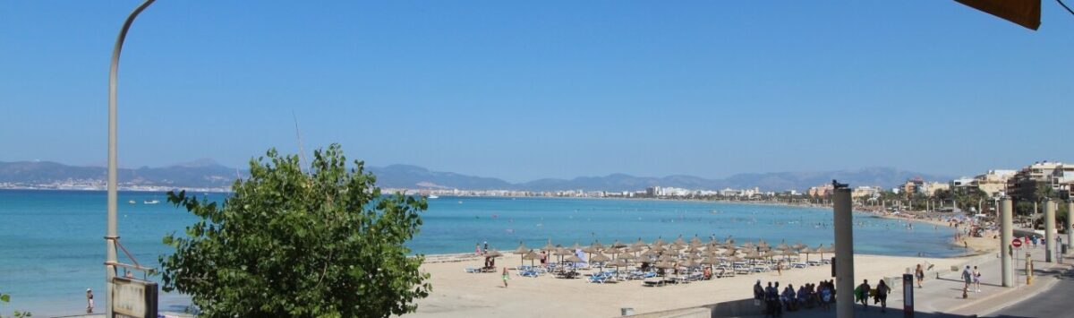 Strandpromenade El Arenal mit türkisblauem Meer, Sonnenschirmen und Bergpanorama – direkte Meereslage der Wohnung