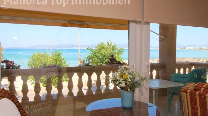 Verglaste Terrasse einer Strandwohnung in El Arenal mit Meerblick, Sitzecke und türkisblauem Mittelmeer.