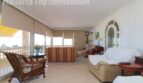 Helles Wohnzimmer mit Rattanstuhl, gestreiften Sofas, Panoramafenster und Meerblick-Terrasse in Meereslinie-Wohnung El Arenal