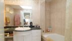 Elegantes Badezimmer mit Marmor-Waschtisch, weißem Unterschrank, Badewanne und beigen Fliesen in Mallorca-Wohnung