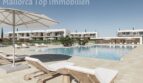 Poolanlage mit Liegestühlen und Sonnenschirmen, moderne Neubauwohnungen in Sa Ràpita im Hintergrund.