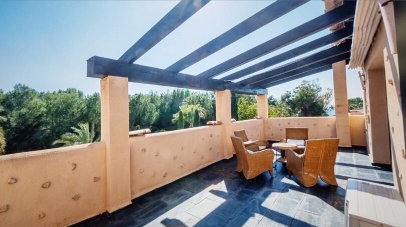 Terraza azotea soleada con pérgola, muebles de ratán y vistas a las palmeras en Calvia