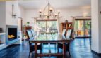 Elegante comedor de la villa en Calvia con mesa de cristal, chimenea y vistas al jardín mediterráneo