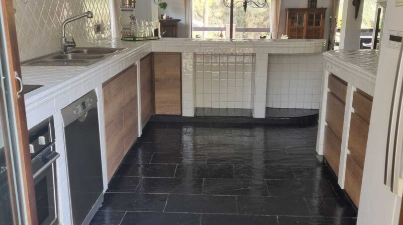 Espaciosa cocina de la villa en Calvia con suelo de pizarra negra, azulejos blancos e isla de cocina