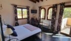 Dormitorio luminoso con techo de vigas de madera, cama de hierro forjado y vistas a las palmeras en villa exclusiva, Calvia