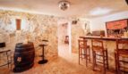 Rústica barra en el sótano de la villa con muros de piedra natural, mostrador de madera, tonel de vino y bola de discoteca en Calvia