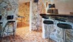 Zona de bar rústica con muros de piedra natural, taburetes de bar y suelo de tablero de ajedrez en villa exclusiva, Calvia.