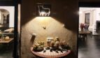 Zona de entrada iluminada de la villa con aplique de pared con forma de toro, decoración de cactus y mesa de mosaico en Calvia.