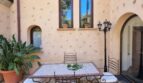 Patio interior mediterráneo de la villa en Calvia con mesa de mosaico, sillas de hierro forjado y muro de piedra natural rústica