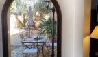 Paso abovedado con vistas al patio interior mediterráneo con muebles de hierro, suelo de piedra y olivo de la villa en Calvia