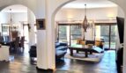 Salón inundado de luz de la villa en Calvia con suelo de piedra, sofás de cuero y elegantes arcos