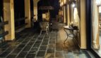 Terraza cubierta con suelo de piedra natural, galerías de arcos y cocina exterior de noche, Villa Calvia