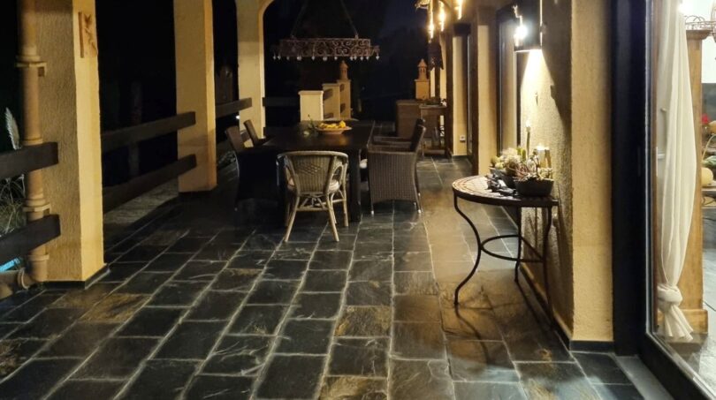 Terraza cubierta con suelo de piedra natural, galerías de arcos y cocina exterior de noche, Villa Calvia