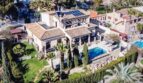 Vista aérea de una villa mediterránea con piscina, paneles solares, terraza y jardín exuberante en Costa de la Calma