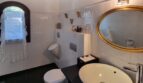 Elegante baño de la villa en Calvià con espejo ovalado dorado, lavabo sobre encimera y ventana de arco