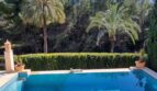 Piscina privada con agua azul turquesa, palmeras y seto bien cuidado de la villa exclusiva en Calvià.