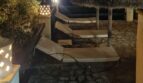 Terraza de piscina iluminada de la villa por la noche con tumbonas, sombrillas de paja y linternas decorativas