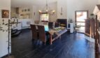 Zona abierta de estar-comedor con suelo de piedra natural oscura, chimenea y zona de cocina en villa exclusiva en Calvia