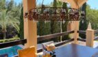 Terraza cubierta con araña de hierro forjado, mesa de comedor y vistas a la piscina, Villa Calvia