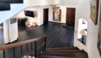 Elegante vestíbulo de entrada con suelo de piedra natural negra, escalera de madera y barandilla de hierro forjado en villa exclusiva en Calvia.