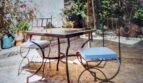 Terraza soleada con muebles de hierro forjado, sombrilla y exuberante vegetación de la villa en Costa de la Calma.