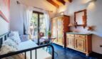 Acogedor dormitorio de la villa en Calvià con armario de madera pintada, techo de vigas de madera y balcón con vistas al jardín.