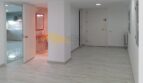 Heller Flur mit Holzboden, Einblick in Bad mit rotem Spiegel und moderne Küche in Hafenwohnung Palma