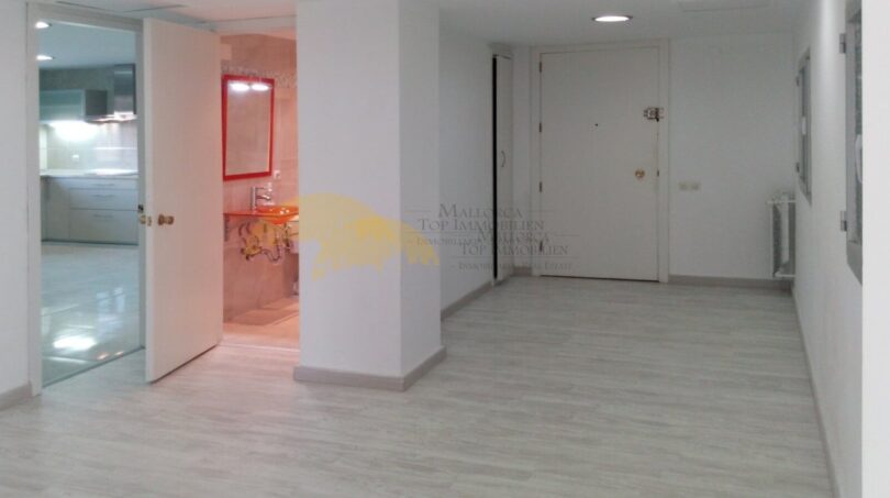 Heller Flur mit Holzboden, Einblick in Bad mit rotem Spiegel und moderne Küche in Hafenwohnung Palma