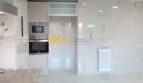 Moderne Einbauküche mit Backofen, Mikrowelle und hellen Marmorfliesen in exklusiver Hafenwohnung Palma