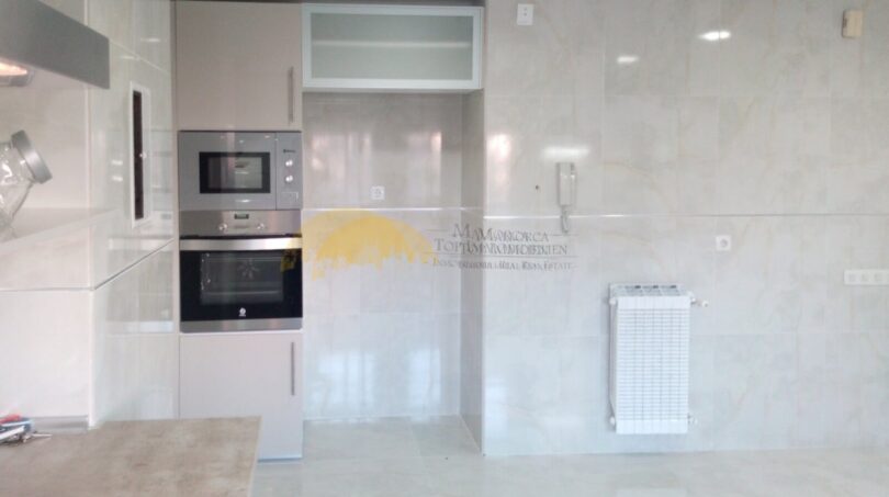 Moderne Einbauküche mit Backofen, Mikrowelle und hellen Marmorfliesen in exklusiver Hafenwohnung Palma