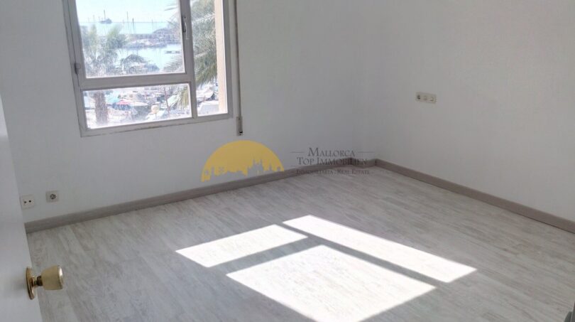 Helles, leeres Schlafzimmer mit Laminatboden und Fenster mit Hafenblick in Palma de Mallorca
