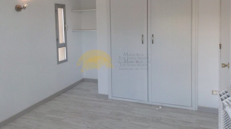 Helles Schlafzimmer mit Einbauschrank, Laminatboden und kleinem Fenster in Hafenwohnung Palma de Mallorca