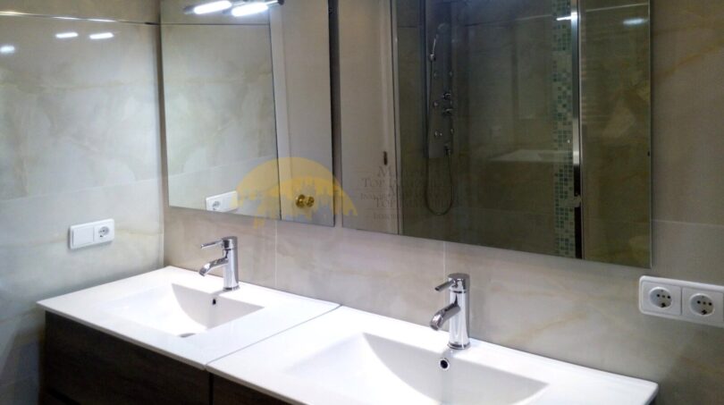 Modernes Badezimmer mit Doppelwaschbecken, Holzunterschrank, großem Spiegel und Dusche in Palma-Hafenwohnung.