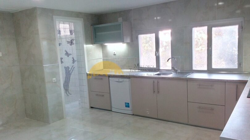 Moderne Küche mit Granitboden, hellen Schränken, Geschirrspüler und Fenster zur Gartenansicht in Palma