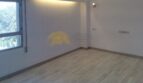 Helles, leeres Zimmer mit Holzboden, Wandleuchte und Fenster mit Grünblick in Hafenwohnung Palma de Mallorca