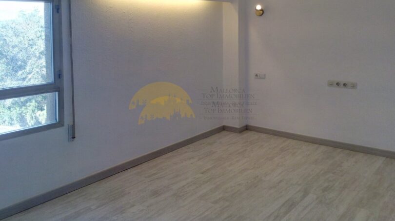 Helles, leeres Zimmer mit Holzboden, Wandleuchte und Fenster mit Grünblick in Hafenwohnung Palma de Mallorca