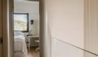 Heller Flur mit Holzboden führt zu modernem Schlafzimmer mit Schreibtisch und Gartenblick