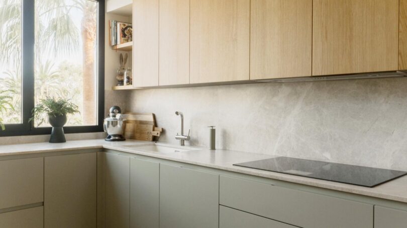 Moderne Designerküche mit Holzfronten, Marmorrückwand und Kochfeld in exklusiver Maisonette, Palma de Mallorca