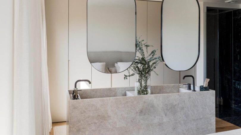 Luxuriöses Marmor-Doppelwaschbecken mit ovalen Designspiegeln und Pflanzendekor in Maisonette-Wohnung, Palma