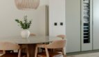 Elegantes Esszimmer mit Marmortisch, Designstühlen, Holz-Pendelleuchte und integriertem Weinkühlschrank in Palma