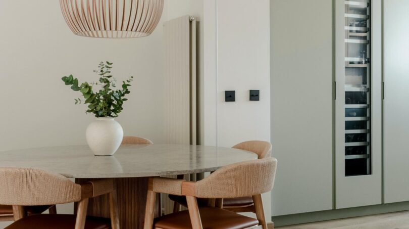 Elegantes Esszimmer mit Marmortisch, Designstühlen, Holz-Pendelleuchte und integriertem Weinkühlschrank in Palma