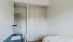 Helles Schlafzimmer der Maisonette mit eingebautem Kleiderschrank, blauem Schreibtisch und Einzelbett