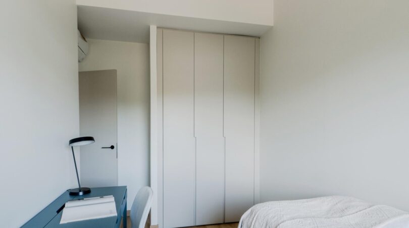 Helles Schlafzimmer der Maisonette mit eingebautem Kleiderschrank, blauem Schreibtisch und Einzelbett
