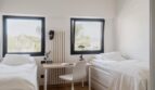 Helles Zweibett-Schlafzimmer mit Schreibtisch, weißer Einrichtung und Panoramafenstern mit Meerblick in Palma