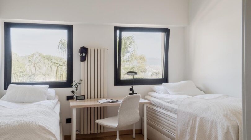 Helles Zweibett-Schlafzimmer mit Schreibtisch, weißer Einrichtung und Panoramafenstern mit Meerblick in Palma
